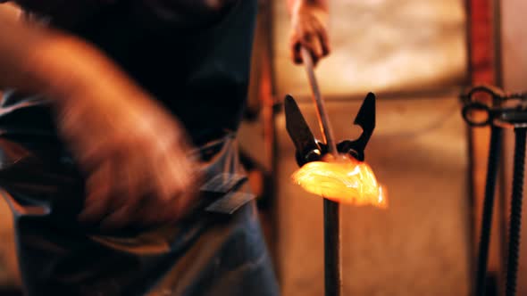 Mid section of glassblower shaping a molten glass