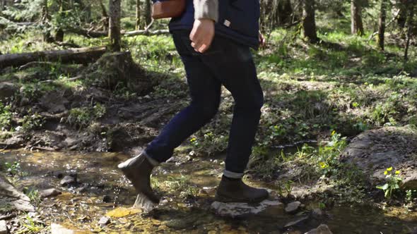 Man Crossing Brook in Green Forest