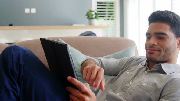 Happy man using digital tablet in living room