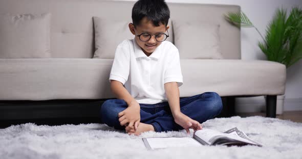 Asian boy wearing glasses reads a book and then plays a game.