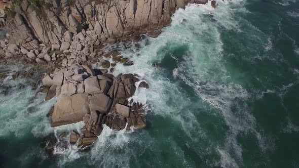 View From a Drone Vertically Down on a Stone Cape Washed By Strong Waves