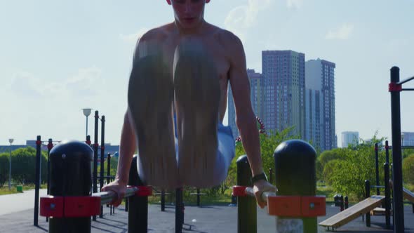 A Man Does a Street Workout on Parallel Bars