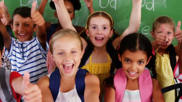 School kids showing thumbs up in classroom