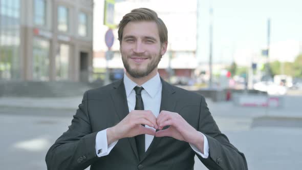 Loving Businessman Showing Heart Shape By Hands Outdoor