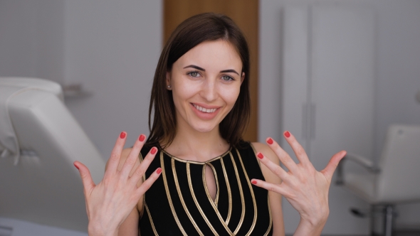 Beauty Parlour. A Happy Girl Shows Off Her New Manicure. Red Nail