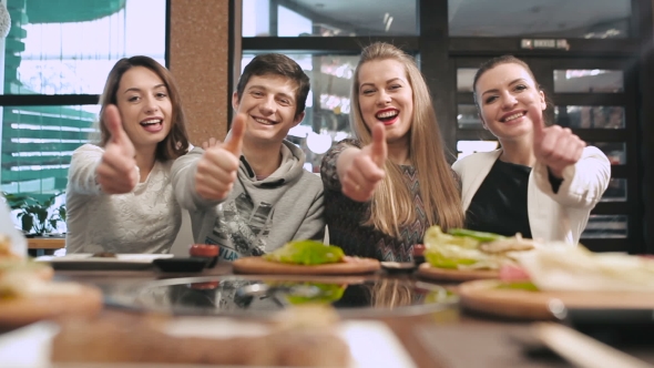 Group Of Friends Showing Thumbs Up In Restaurant alt