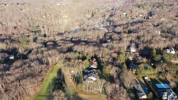 an aerial view over the edge of a pristine golf course, on a sunny day. Surrounding the golf course