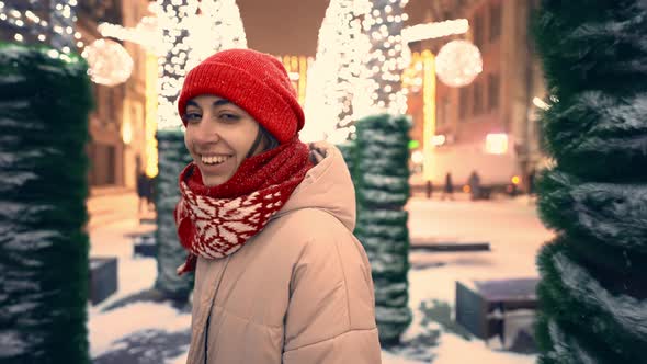 Gimbal Shot of Happy Smiling Gorgeous Woman in Knitted Red Cap and Scarf Walking on City Square with