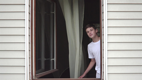 Smiling Teenage Boy In Open Window