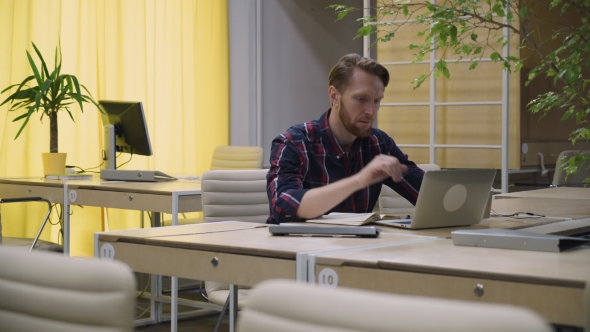 Bearded Businessman Working At a Computer And  Drinking Coffee. alt