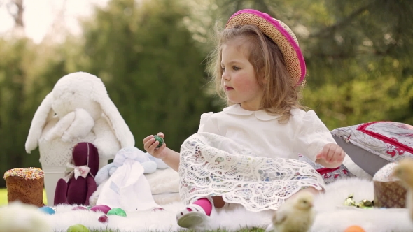 Happy Child Sits On a Meadow Around Easter Decoration