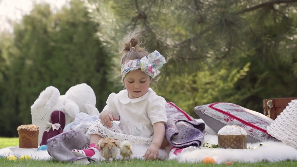 Happy Child Sits On a Meadow Around Easter Decoration