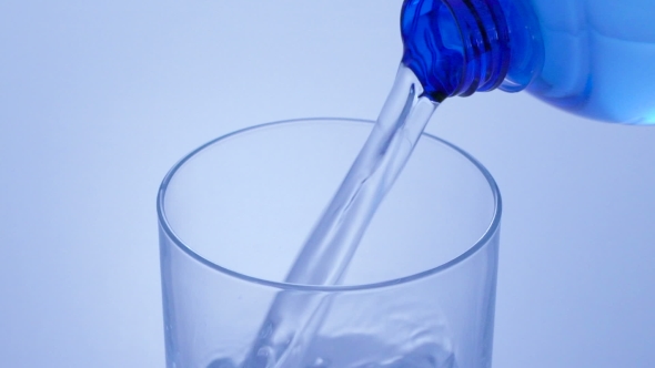 Pouring Water From Bottle Into Glass In Blue Toning alt