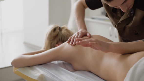 Smiling Young Woman Getting Massage Treatment From Masseuse