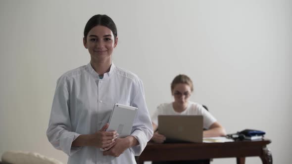 Portrait of Young Professional Female Doctor Holding Laptop While Looking at the Camera. In the