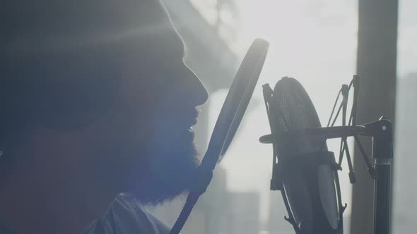 Closeup of the Attractive Bearded Man Singing Into a Microphone in Sun Backlight