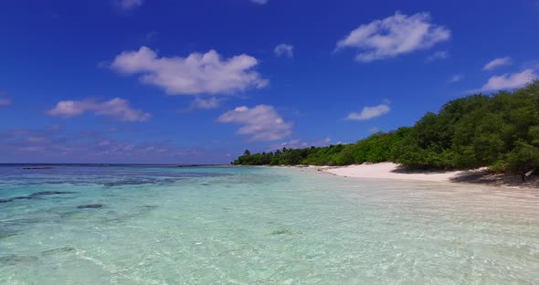 Wide angle flying tourism shot of a white paradise beach and turquoise sea background in 4K