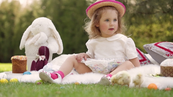 Happy Child Sits On a Meadow Around Easter Decoration