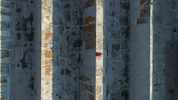 Man relaxes lying on roof of sunlit building with geometric patterns. Aerial panning