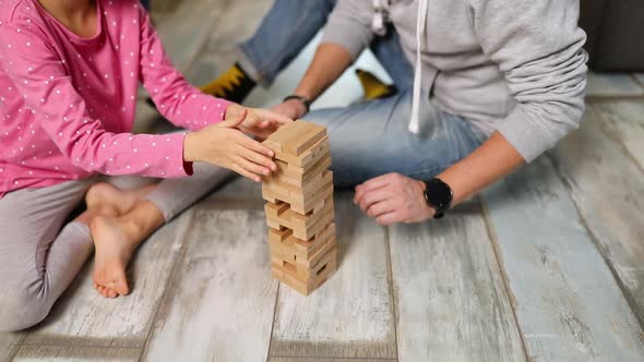 Happy father and daughter play game with wooden tower blocks bricks