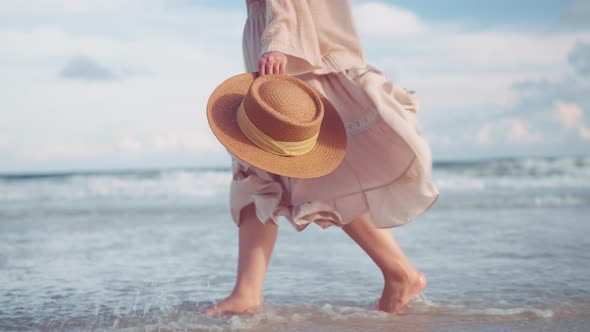 Woman feet walking along sea water waves on sandy beach