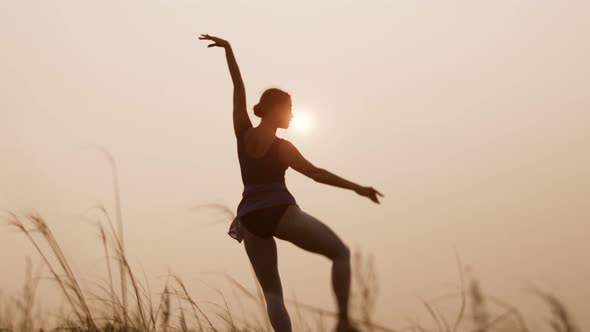 Woman is engaged in ballet against background of sun and sky outside, front view. Woman elegantly an