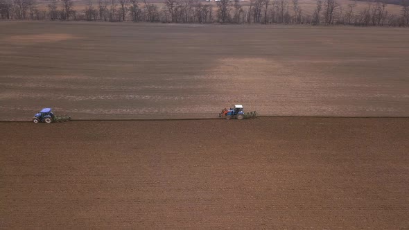 Agricultural Work in the Field, Two Blue Tractors Plow the Land