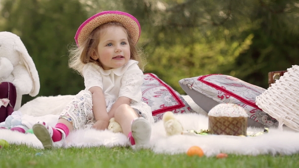 Happy Child Sits On a Meadow Around Easter Decoration