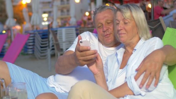 Couple Sitting And Looking At Phone