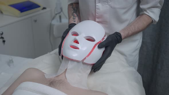 Male Beautician Taking Off Red LED Light Therapy Device From Face of Male Client in Spa Salon