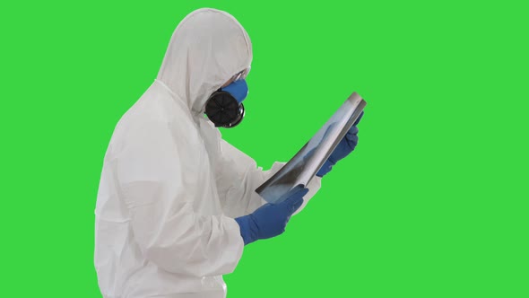 Doctor in Protective Suit Looking at Lungs X-ray While Walking on a Green Screen, Chroma Key.