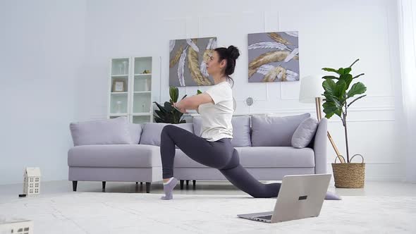 Young Woman in Fitness Clothes Doing Stretching Exercises in the Living Room