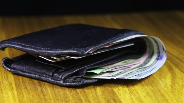 Money In a Wallet Rotating On a Wooden Table