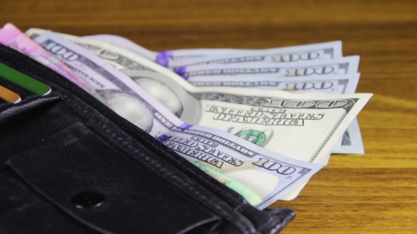 Money In a Wallet Rotating On a Wooden Table