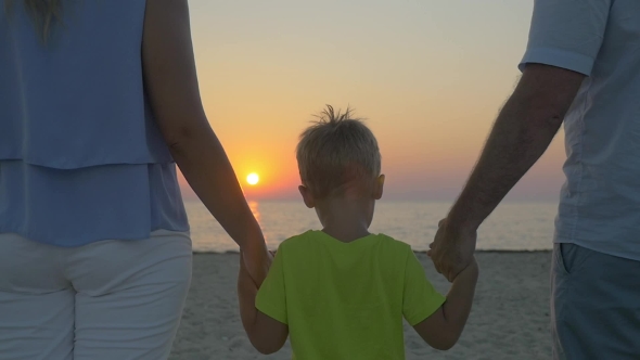 Family With Child Looking At Sunset Over Sea