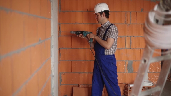 The Electrician Performs Electrical Installation Using a Drill