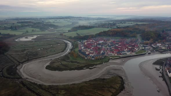 Aerial footageing forward over Wivenhoe in Essex at sunrise with mist and the bend of the river coln