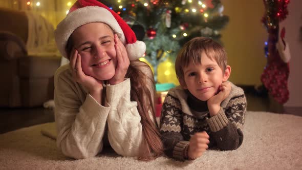 Smiling Boy with Mother Lying on Carpet Under Christmas Tree While Celebrating New Year