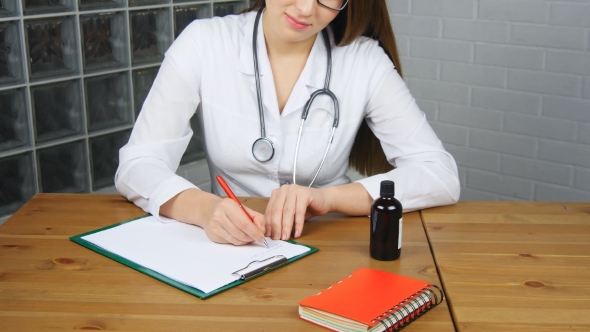 Beautiful Young Female Doctor Sitting In Front Of Working Table