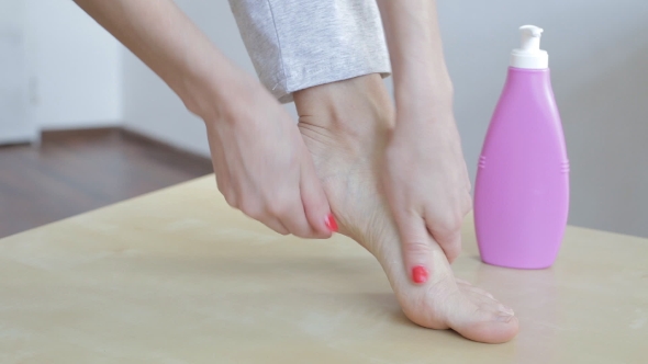 Woman Applying Cream On Foot