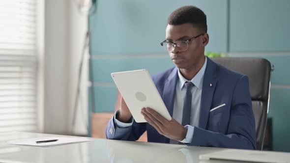 Young African Businessman Using Tablet While Sitting in Office