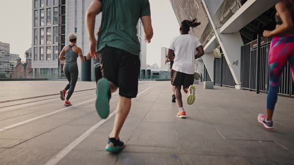 Progressive Endurance Athletes in Portable Shoes and Clothing Run Through the City Streets