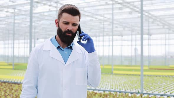 Agricultural Engineer in a Greenhouse Using Mobile, Talking on Smartphone