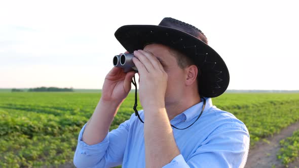 Surprised Look of a Young Agronomist Looking Through Binoculars at Field