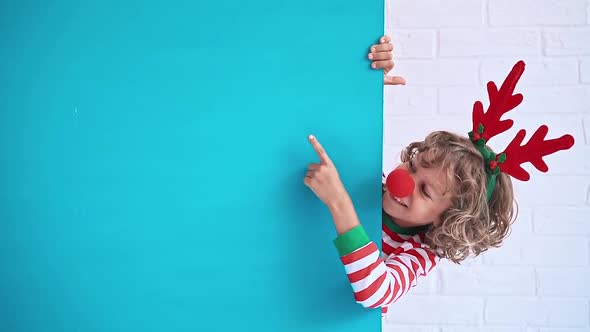 Funny Kid Holding Blue Cardboard Banner Blank. Child Playing At Home. Christmas Holiday Concept alt