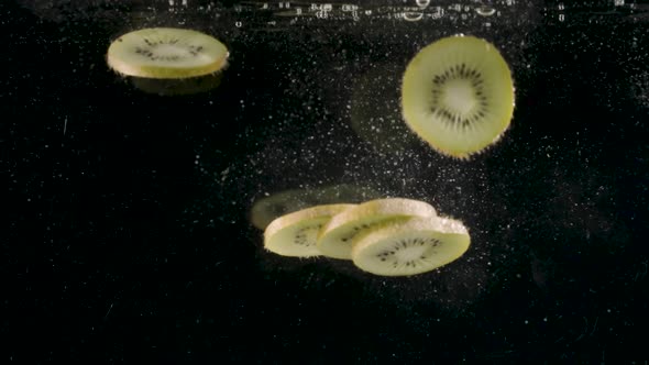 Slices of kiwi fruit drop into water