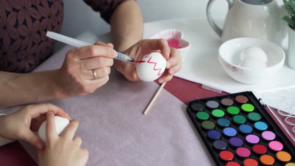 Mom and son coloring Easter eggs at the kitchen table