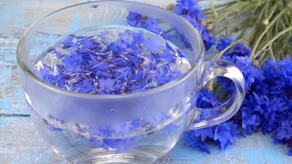 Brewing a tisanes from knapweeds flowers in a transparent cup.