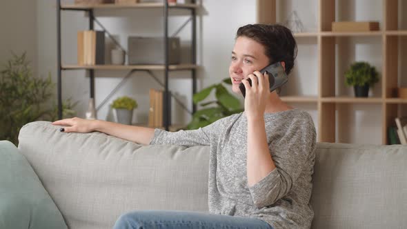 Young Beautiful Woman Resting on Comfy Soft Couch in Living Room Holding Smart Phone Enjoy Pleasant