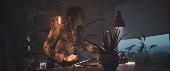 Woman working at desk picks up camera